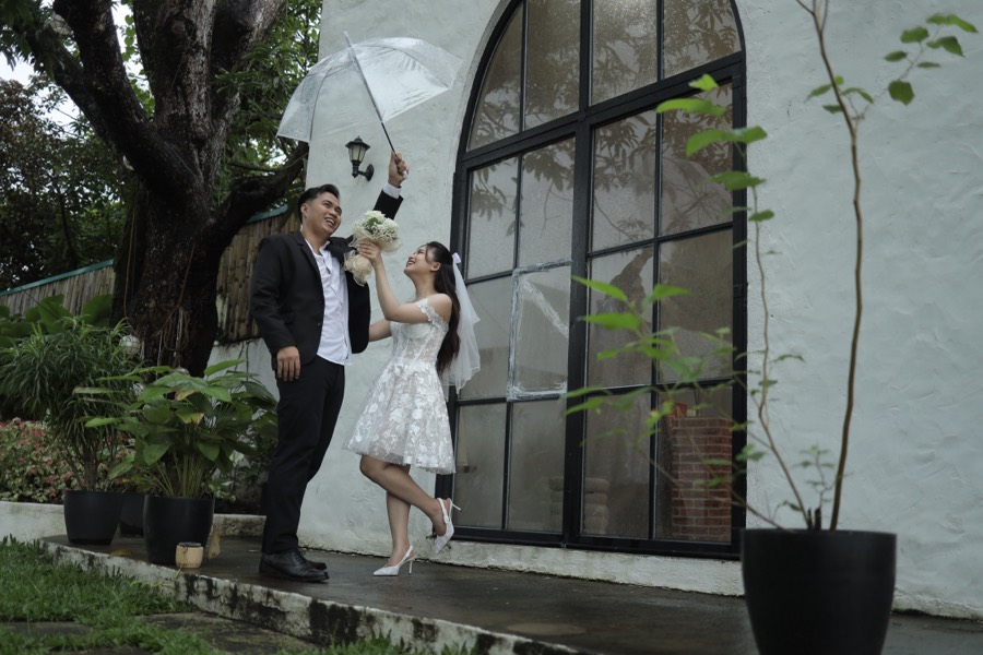 John and Alyssa laughing as they raise their umbrella by the chapel